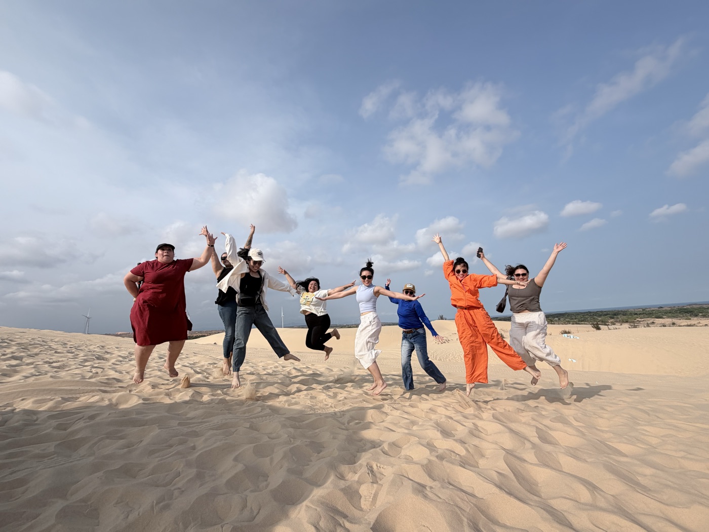 The Movement team leaping together on the sand dunes in Vietnam